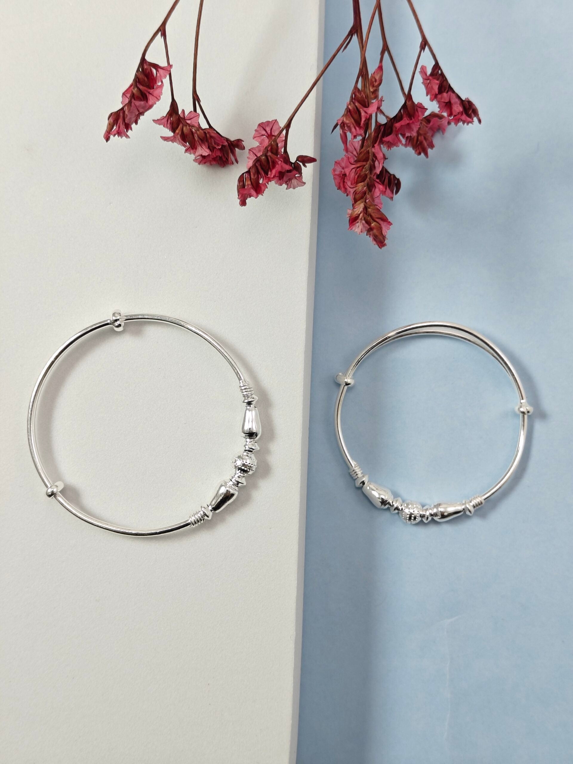 Silver hoop earrings on a light gray and blue gradient background with dried pink flowers.